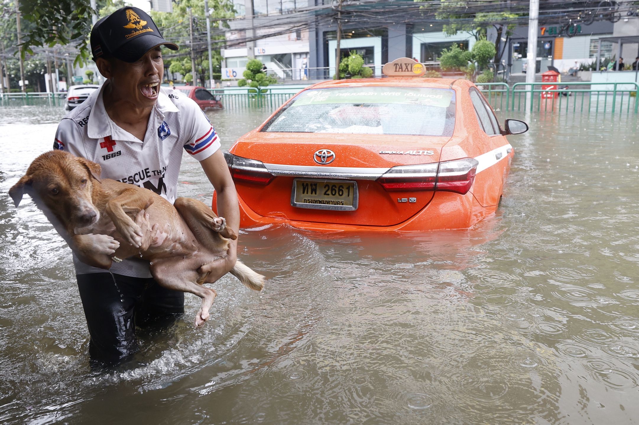A Thai man holds a dog while wading through floodwater next to a submerged abandoned car along Phetchaburi Road in Bangkok, Thailand, 26 September 2026. All 50 districts in Bangkok have been declared flood disaster zones following persistent heavy rain caused by a strong low-pressure system combined with seasonal monsoon patterns. EPA/RUNGROJ YONGRIT Dostawca: PAP/EPA.