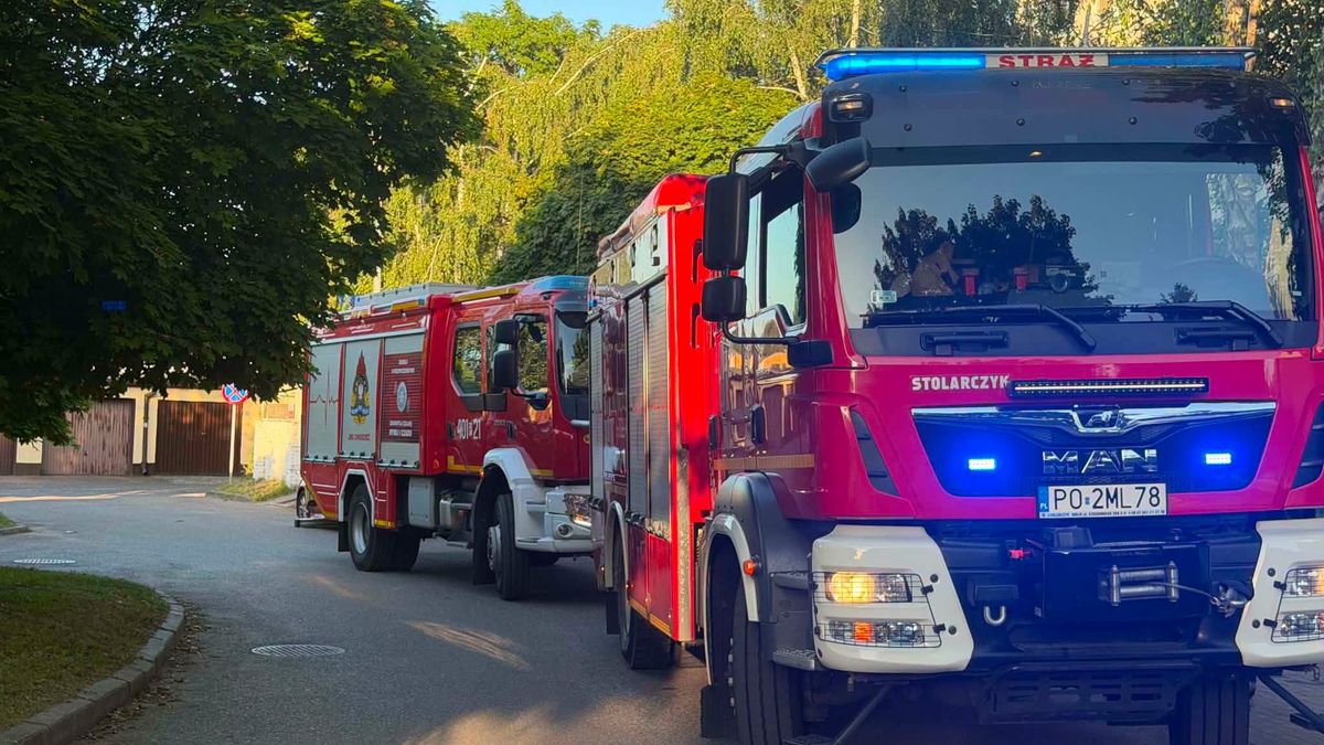 Wóz strażacki jednostki OSP lub PSP na tle budynków mieszkalnych
