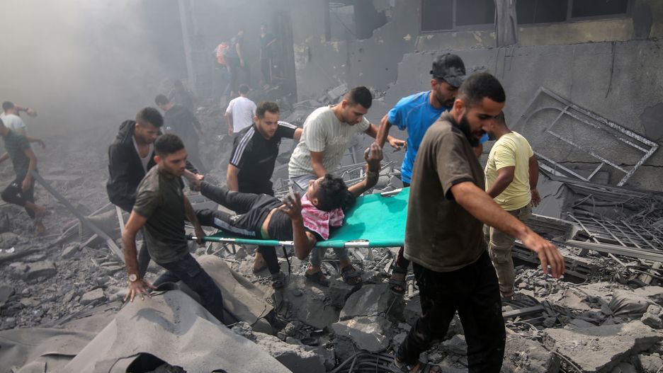 RAFAH, GAZA - OCTOBER 12: People carry an injured man on a stretcher among rubbles of destroyed buildings as Israeli airstrikes continue on the sixth day in Rafah, Gaza on October 12, 2023. (Photo by Abed Rahim Khatib/Anadolu via Getty Images)