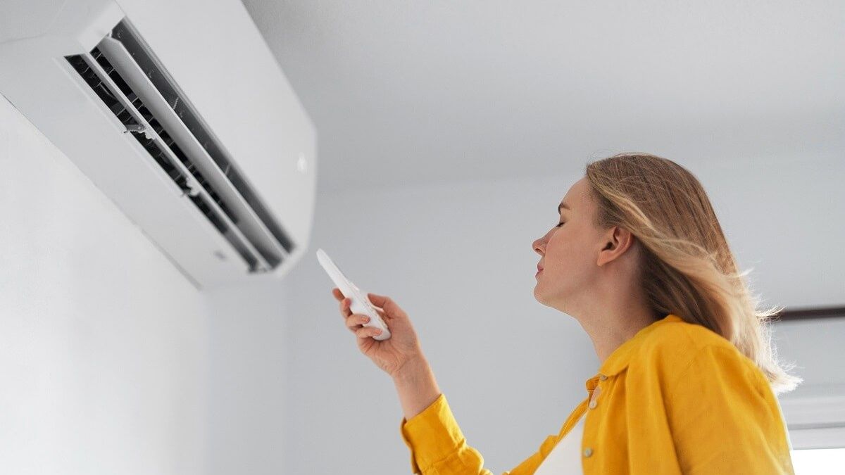 Kobieta stoi przed klimatyzatorem