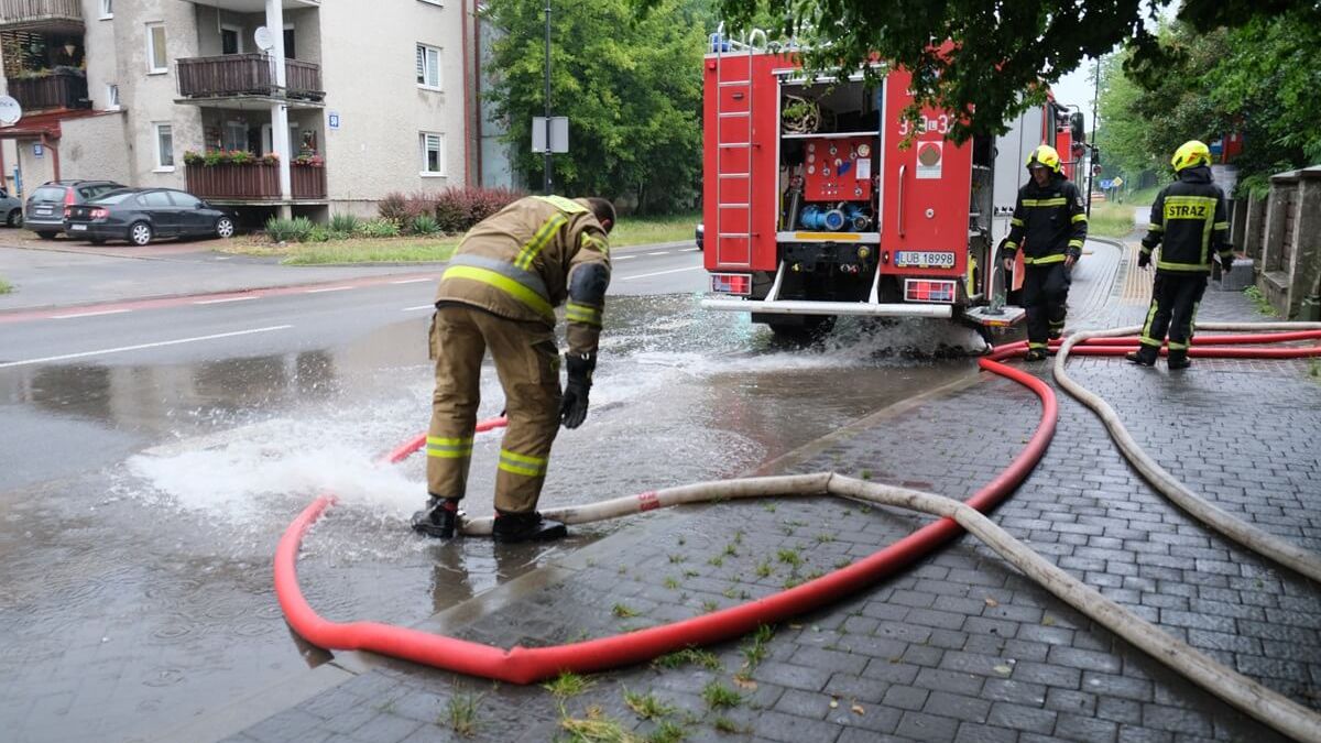 Strażacy wypompowujący wodę z zalanej posesji