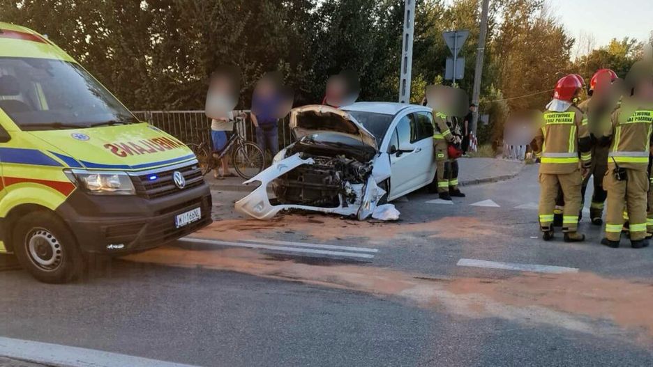 Karetka pogotowia oraz strażacy interweniują przy uszkodzonym samochodzie osobowym na drodze.