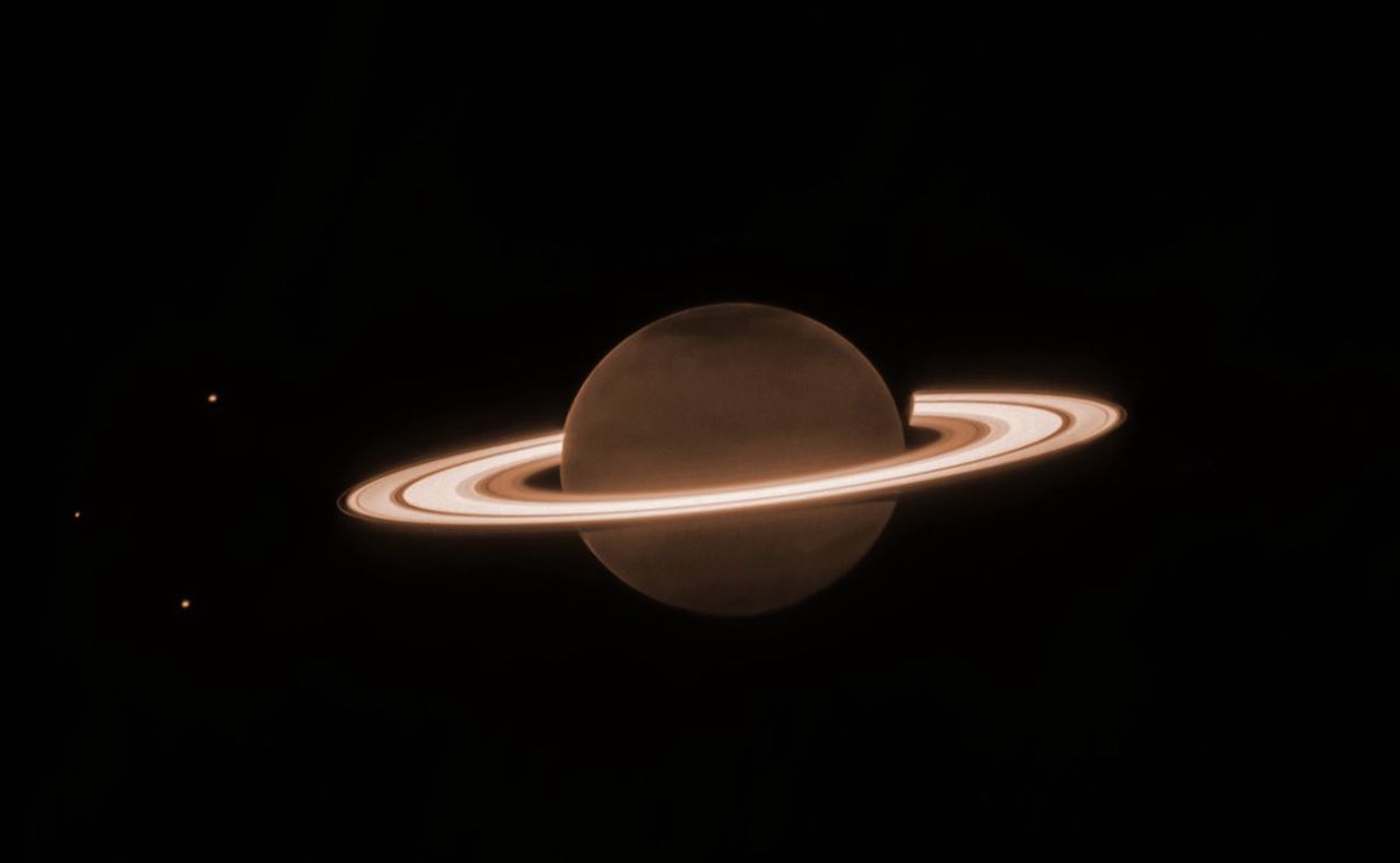 Saturn z doskonale widocznymi pierścieniami i księżycami.