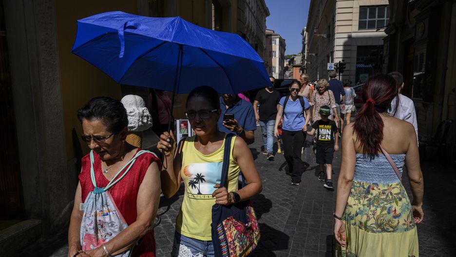 ROME, ITALY - JULY 23: Tourists hold an umbrella for shade during an ongoing heatwave with temperatures reaching 37 degrees, on July 23, 2024 in Rome, Italy. (Photo by Antonio Masiello/Getty Images)