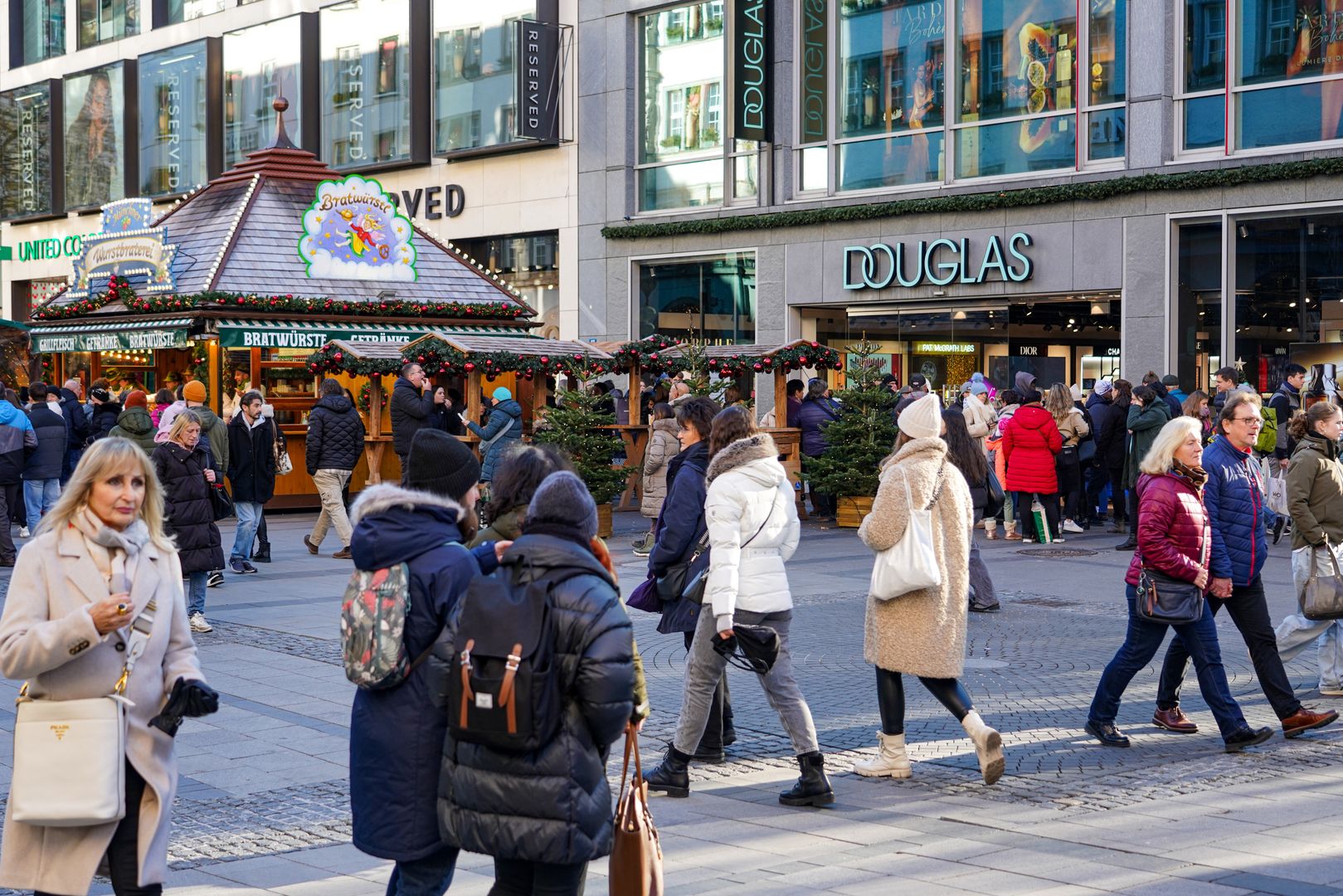 A bustling shopping street in Munich, Bavaria, Germany, on November 30, 2024, is alive with the festive spirit as shoppers fill the streets, admire holiday decorations, and select Christmas gifts. The atmosphere is lively, with a sense of excitement for the upcoming holidays. Kaufinger Strasse in Munich is crowded as many people are out shopping for Christmas gifts. The store windows are decorated with festive displays, showcasing a wide range of gifts and holiday items. Passersby stop to admire the windows and choose presents for the upcoming holiday season. Numerous Christmas stalls in the middle of the street invite people to drink mulled wine or eat snacks. As one of Munich's central shopping streets, Kaufinger Strasse attracts both locals and tourists who are completing their pre-Christmas shopping. The festive atmosphere is enhanced by the Christmas decorations and the increasing number of shoppers in the stores. The street becomes a lively spot for those looking to buy gifts and experience the holiday spirit. (Photo by Michael Nguyen/NurPhoto via Getty Images)