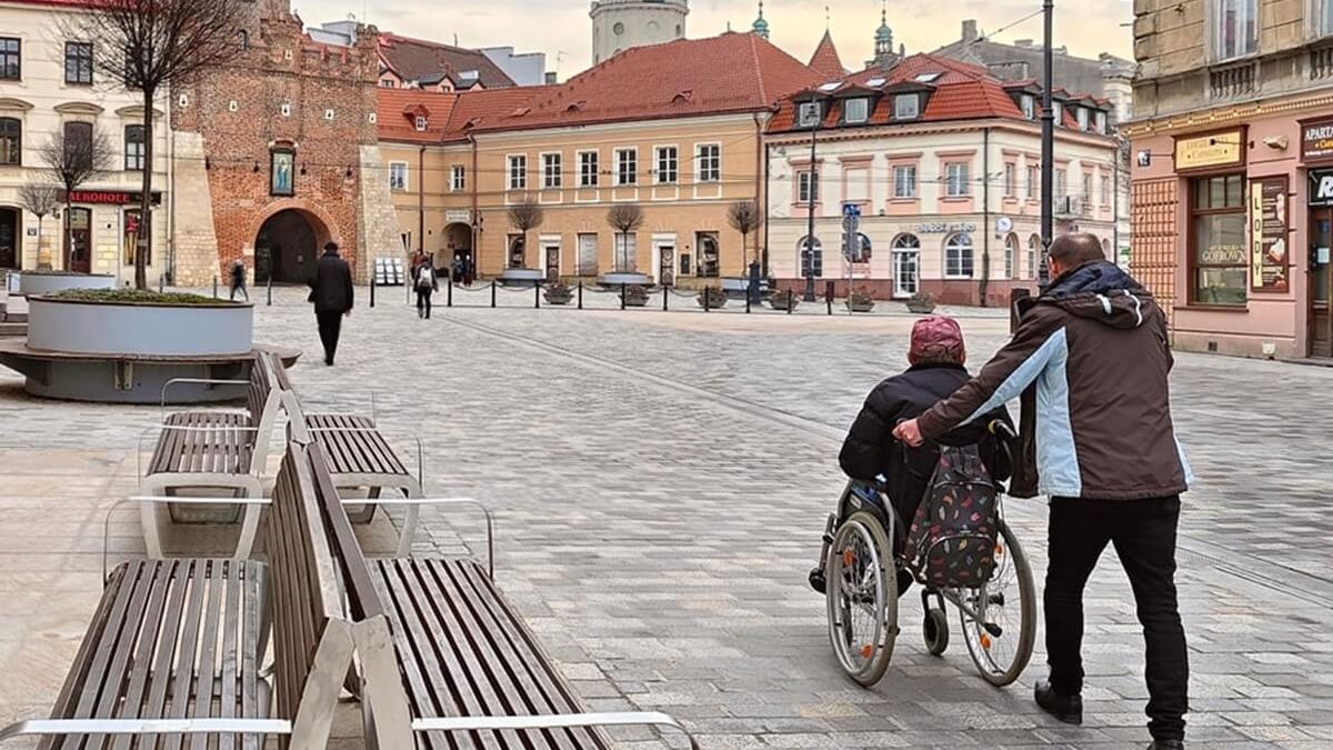 Mężczyzna pchający kobietę na wózku inwalidzkim