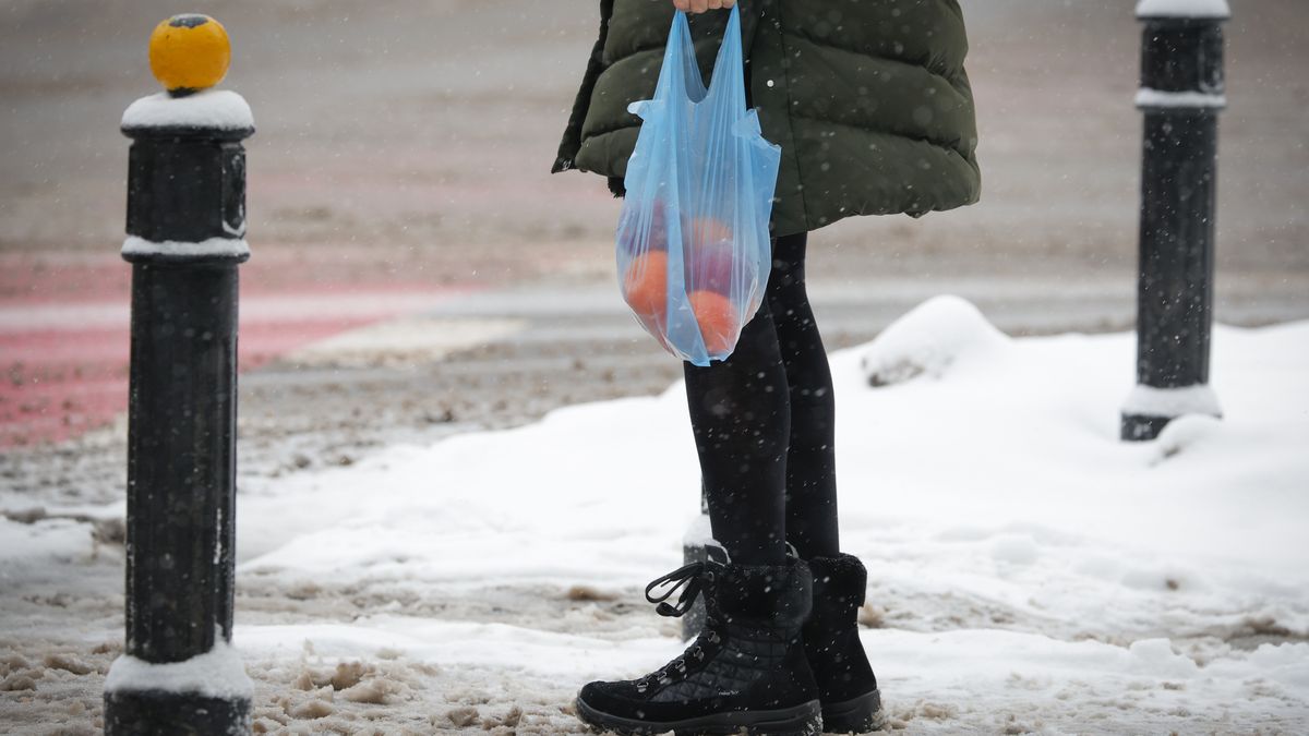 A woman carries a plastic grocery bag with fruit oranges and apples in Warsaw, Poland on 16 December, 2022. Poland sees heavy snowfall for the sixth consequetive day with nightly temperatures in some ares of the country falling to nearly minus 20 degrees Centigrade. (Photo by STR/NurPhoto via Getty Images)