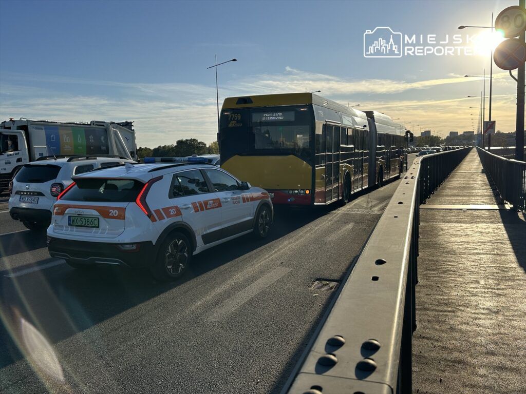 Kierowca samochodu osobowego zatrzymany obok autobusu w godzinach szczytu na ruchliwej drodze.