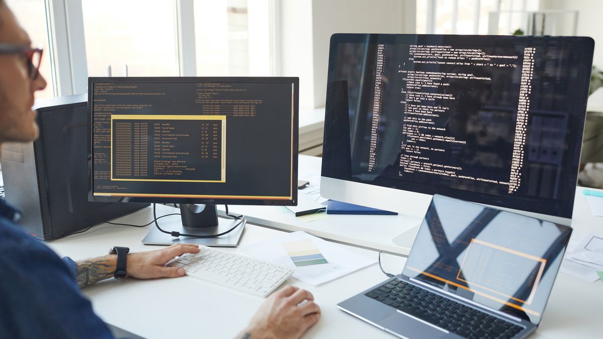 IT Programmer Writing Code on Computer ScreenSide view at male programmer writing code while using multiple computers in IT developers office , copy spaceoccupation, place of work, businessman, using computer, design, sitting, computer monitor, working, planning, desktop pc, business, modern, IT, connection, software, data, IT developer, computer programmer, software engineer, programmer, typing, programming, website, engineer, developer, development, online, internet, security, writing, code, computer scientist, production, office, work, entrepreneur, computer, technology, website designer, web, analyst, male, man, mobile, screen