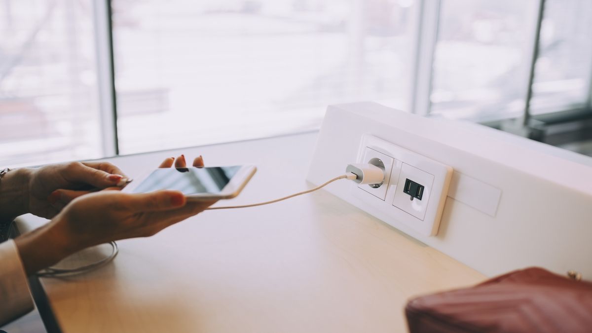 Cropped hands of young businesswoman charging smart phone at table while waiting in airport departure area
Maskot