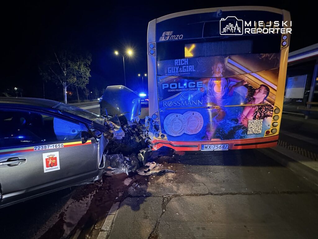 W nocy, samochód osobowy z widocznymi uszkodzeniami zderza się z autobusem, obok świecą niebieskie światła policyjne.