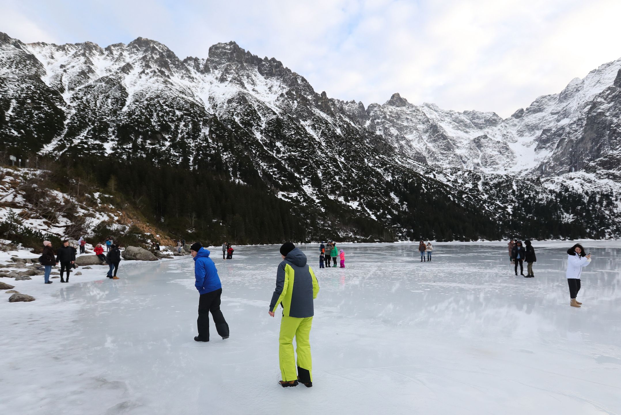 Tatry, Morskie Oko, 26.12.2022. Turyści na tafli lodu na jeziorze Morskie Oko w Tatrach, 26 bm. Tatrzański Park Narodowy ostrzega przed wchodzeniem na zamarznięte górskie jeziora � z powodu panujących w ciągu dnia dodatnich temperatur lód jest bardzo cienki i grozi załamaniem. (jm) PAP/Grzegorz Momot