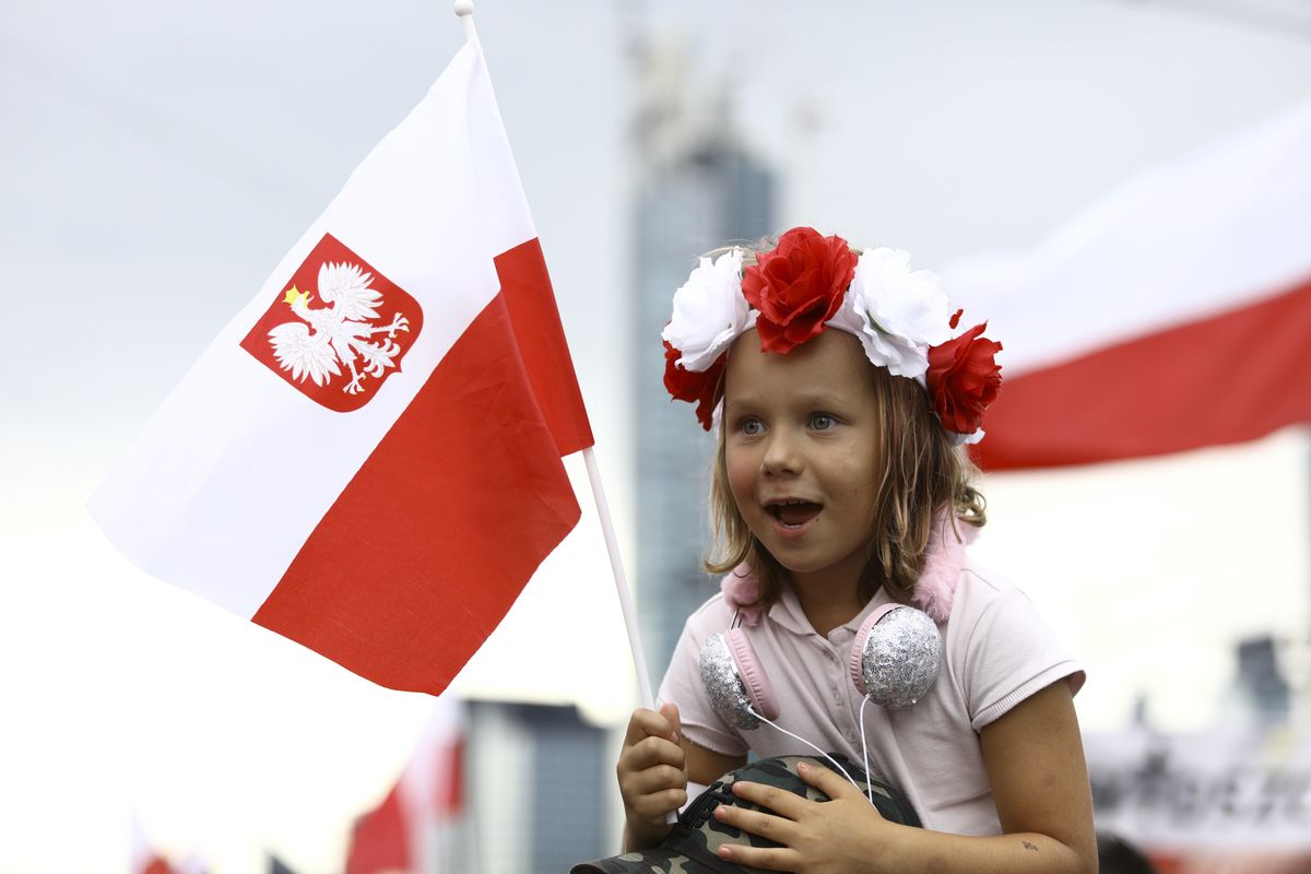 A young girl with a Polish flag with the symbol of the second World War underground army is seen during the 77th anniversary of the Warsaw Uprising in Warsaw, Poland on August 1, 2021. Several thousand people came togehter in the city center where sirens were set off for exactly one minute at five o'clock local time. Every year on August 1 in Poland the anniversary of the uprising of Polish underground fighters against the German Nazi occupiers is remembered. The Warsaw Uprising was the single, largest resistance movement of the second World War. (Photo by STR/NurPhoto via Getty Images)