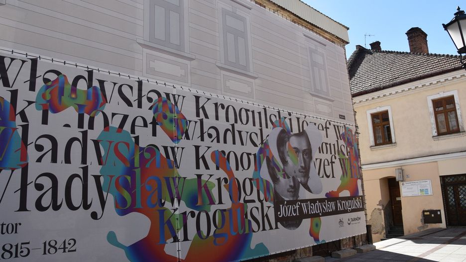 Wielkoformatowy wydruk, który zasłonił spaloną kamienicę od strony Rynku, składa się z dwóch części. Dolna dedykowana jest Józefowi Władysławowi Krogulskiemu