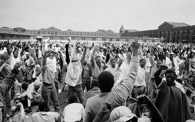 Więźniowie na dziedzińcu D, w bojowych nastrojach, wznoszą pięści w geście ruchu Black Power;
10 września. (Dzięki uprzejmości Associated Press)
