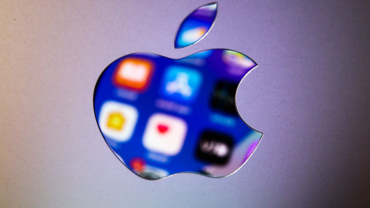 Icons displayed on iPhone screen are seen reflected in Apple logo on MacBook in this illustration photo taken in Krakow, Poland on April 13, 2022. (Photo Illustration by Jakub Porzycki/NurPhoto via Getty Images)