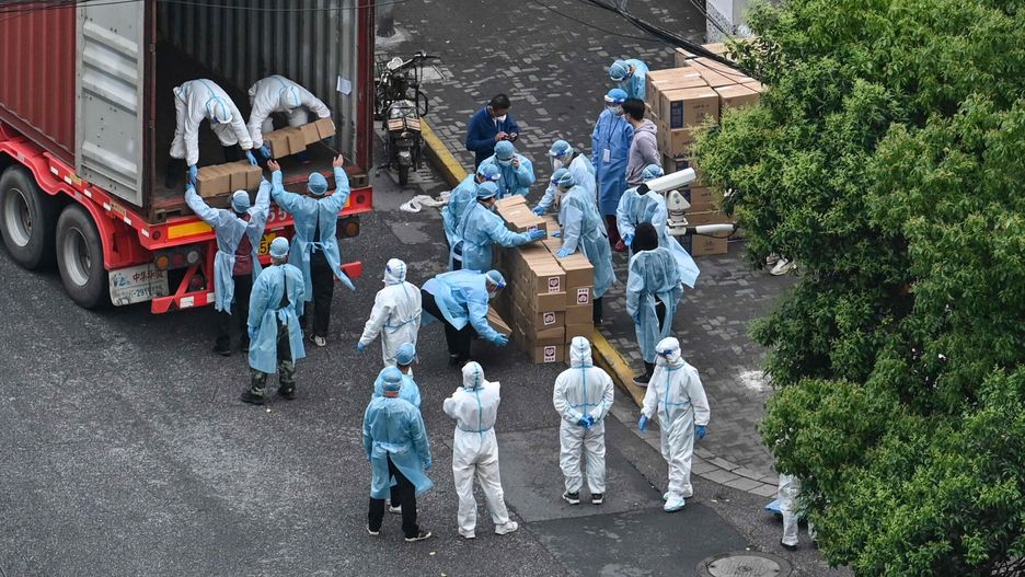 arch50TOPSHOT - Workers wearing protective gear unload boxes from a truck during a Covid-19 coronavirus lockdown in the Jing'an district in Shanghai on May 13, 2022. (Photo by Hector RETAMAL / AFP)HECTOR RETAMAL