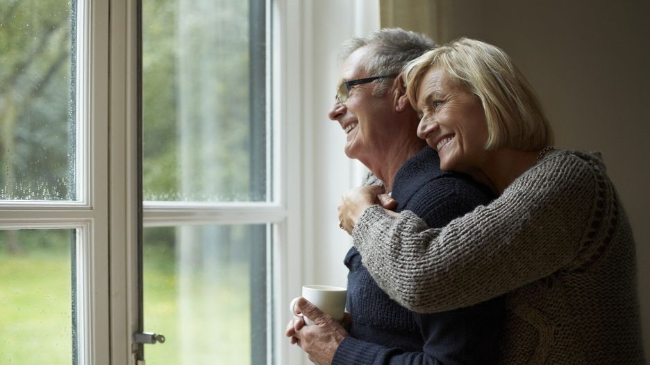 Senior woman embracing man in front of door