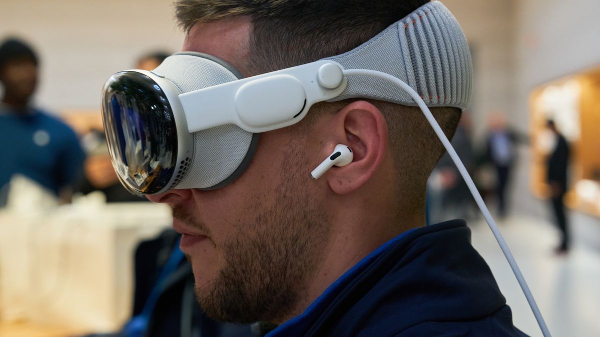 An employee of Rosellimac, an authorized reseller of Apple products, tries the Apple Vision Pro mixed reality (XR) headset while wearing AirPods at the company's Fifth Avenue store in New York, US, on Friday, Feb. 2, 2024. Apple Inc.'s first major new product in nine years arrives on Friday as the Vision Pro, a $3,499 mixed-reality headset, goes on sale in the US. Photographer: Bing Guan/Bloomberg via Getty Images