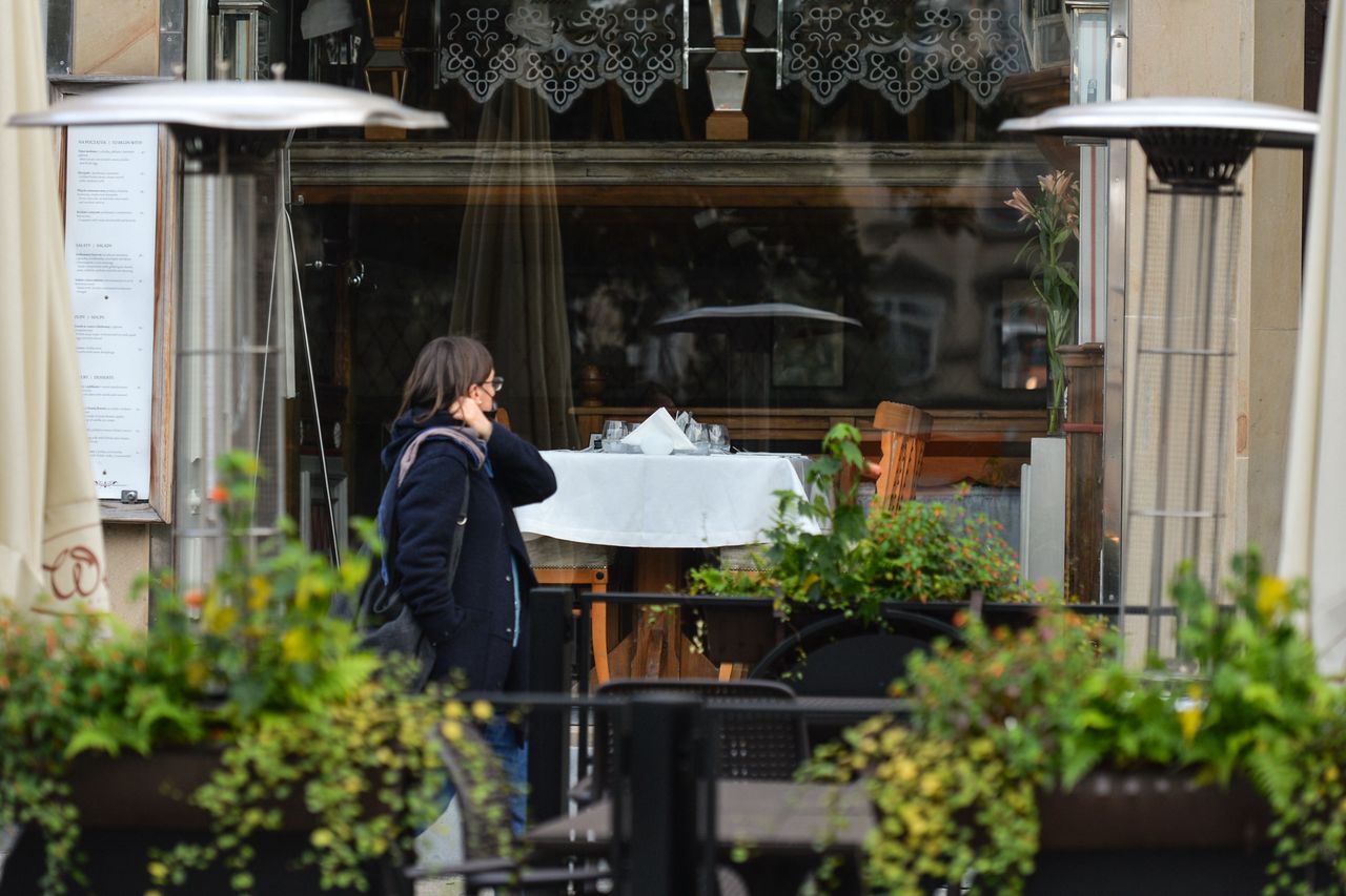 Kobieta przechodząca obok zamkniętej restauracji 