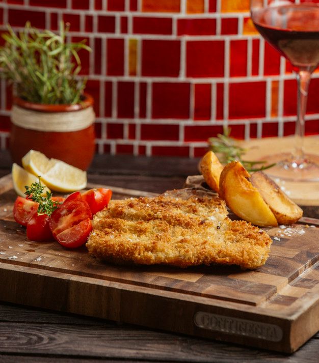 fried chicken patties served with fried potatoes, lemon and tomato on wood board