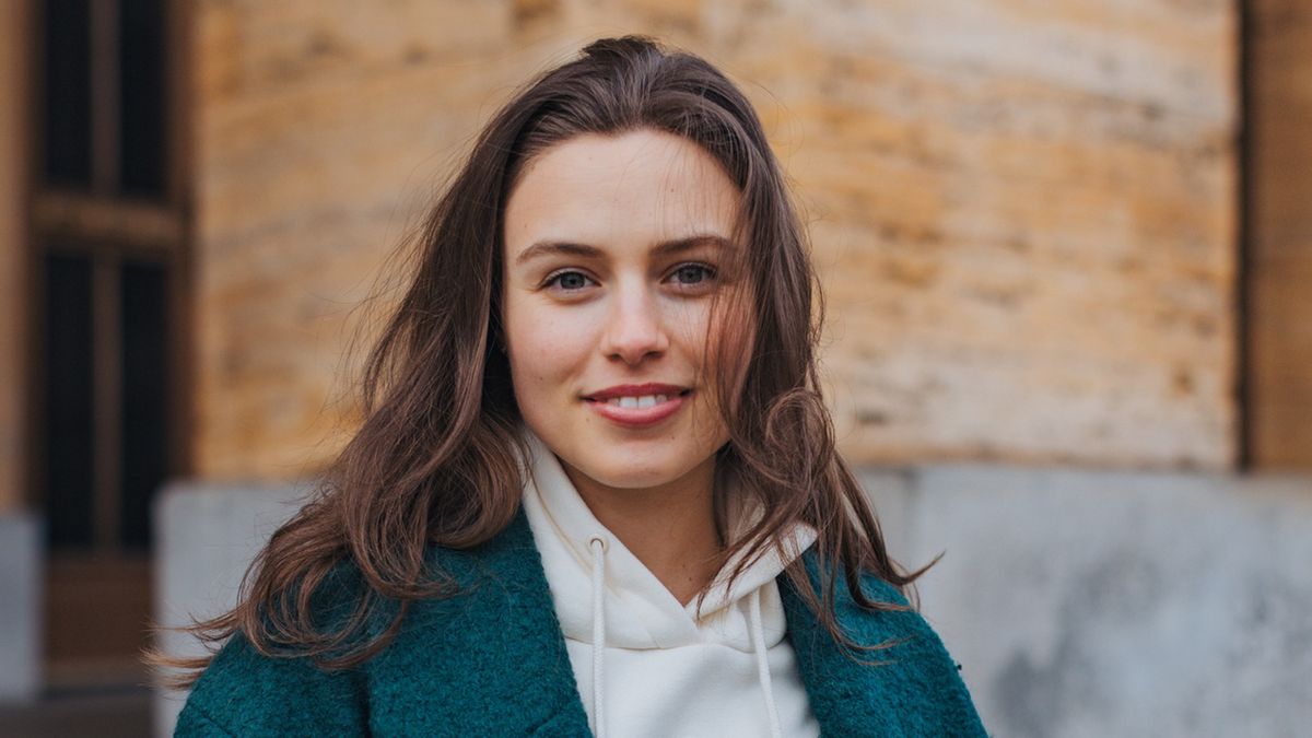 Portrait of beautiful young woman in the city. Standing on city street, university student in front of university building. Fashionable Gen z woman smiling, looking at camera.Portrait of beautiful young woman in the city. Standing on city street, university student in front of university building. Fashionable Gen z woman smiling, looking at camera.Halfpoint Images