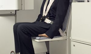 Dlaczego stewardesy siadają na dłoniach? Tłumaczymy, o co chodzi