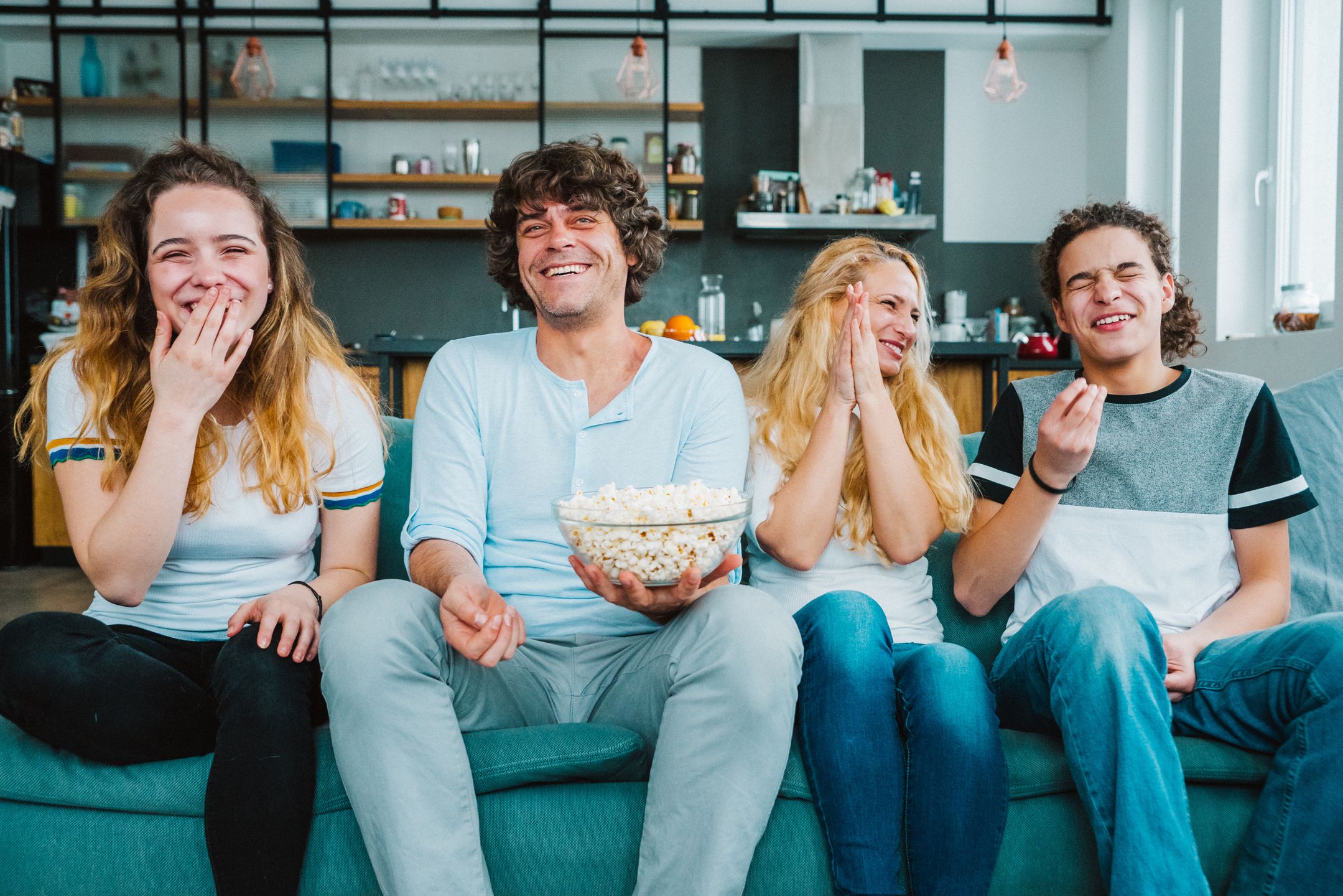 Family sitting on the sofa at home and eating popcorn