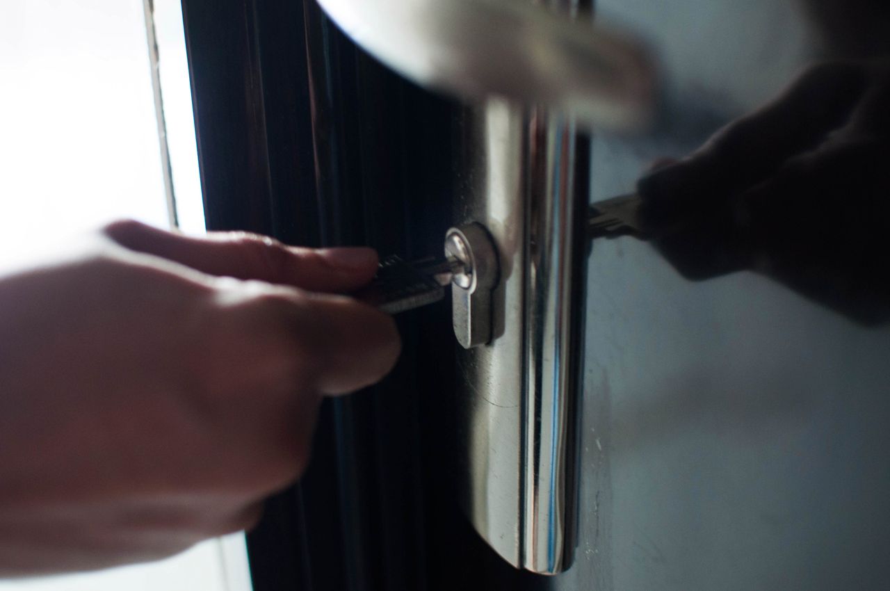 A man is holding a key to open the lock door indoor apartment
