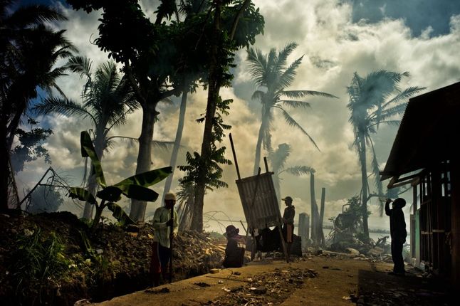 Wyróżnienie w kategorii Krajobraz. Trzy miesiące po tajfunie Yolanda (Hayan) miasto Tacloban na filipińskiej wyspie Leyte powoli wraca do życia. Mieszkańcy z trudem odbudowują swoje domostwa. Widok palących się śmieci na tle połamanych palm ciągnie się po horyzont.