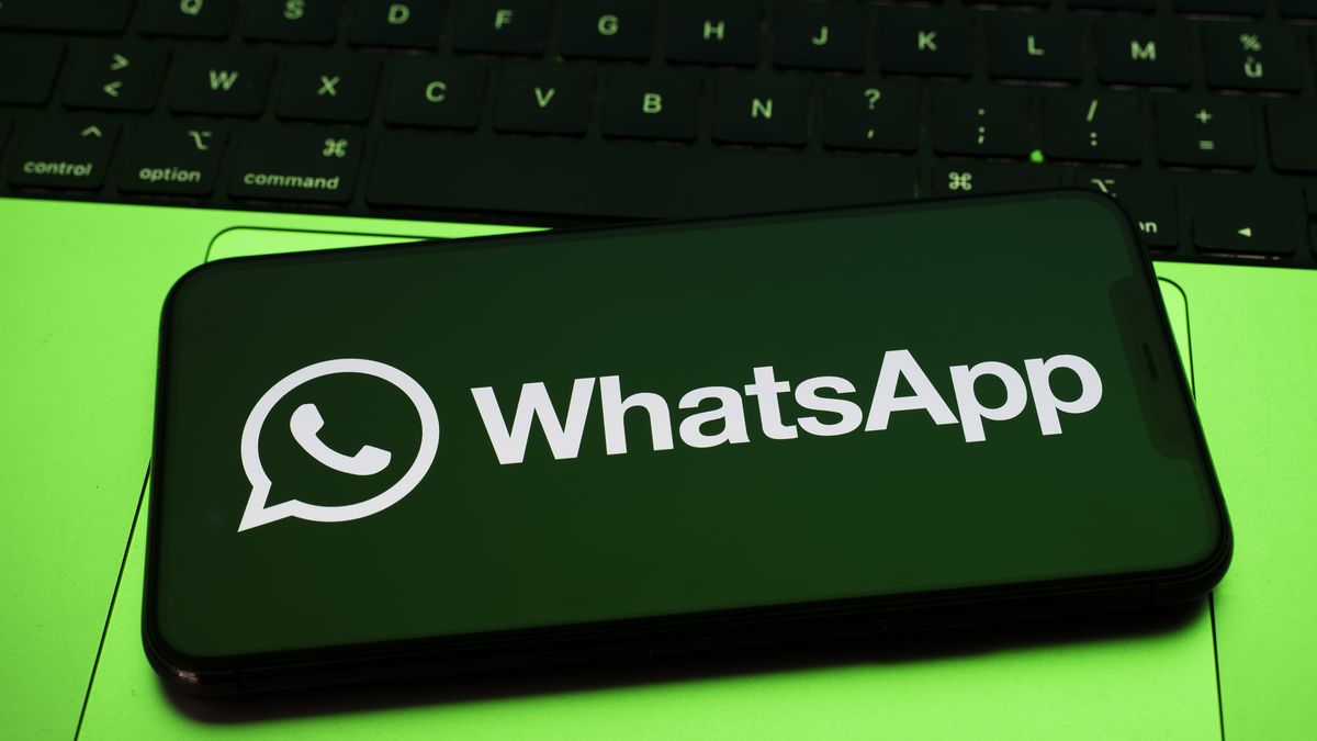 In Créteil, France, on September 29, 2025, the WhatsApp logo appears on a smartphone placed on a laptop keyboard, which reflects a green light. Meta, the parent company of WhatsApp and Meta AI, makes the Artificial Intelligence assistant mandatory in its instant messaging app. (Photo Illustration by Samuel Boivin/NurPhoto via Getty Images)
