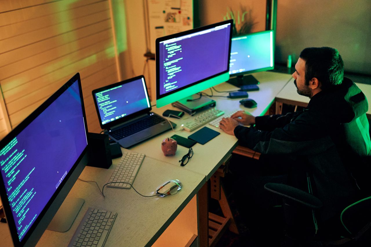 Young male hacker sitting in a room, working on his computer