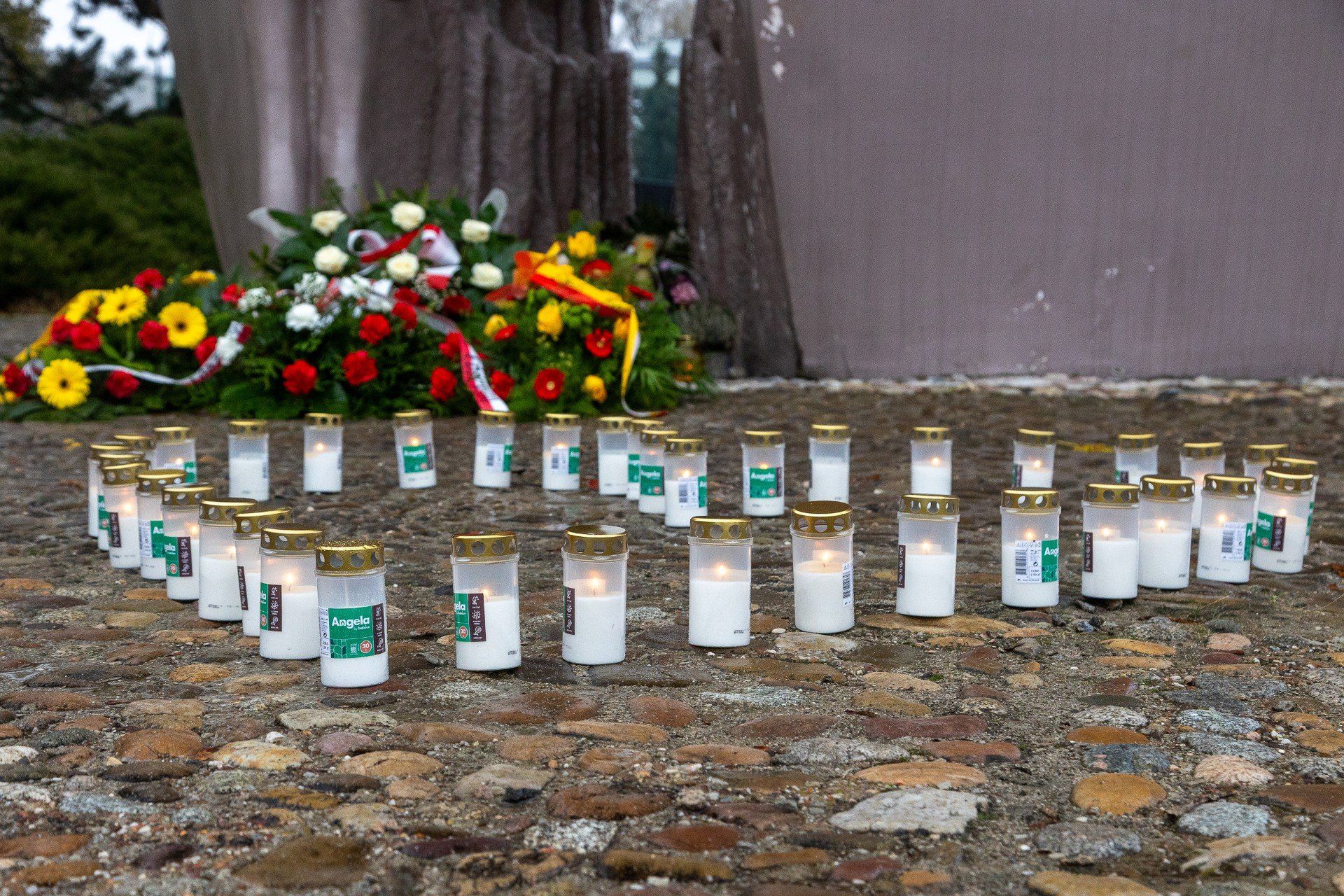 Znicze w kształcie serca zapalone pod pomnikiem.