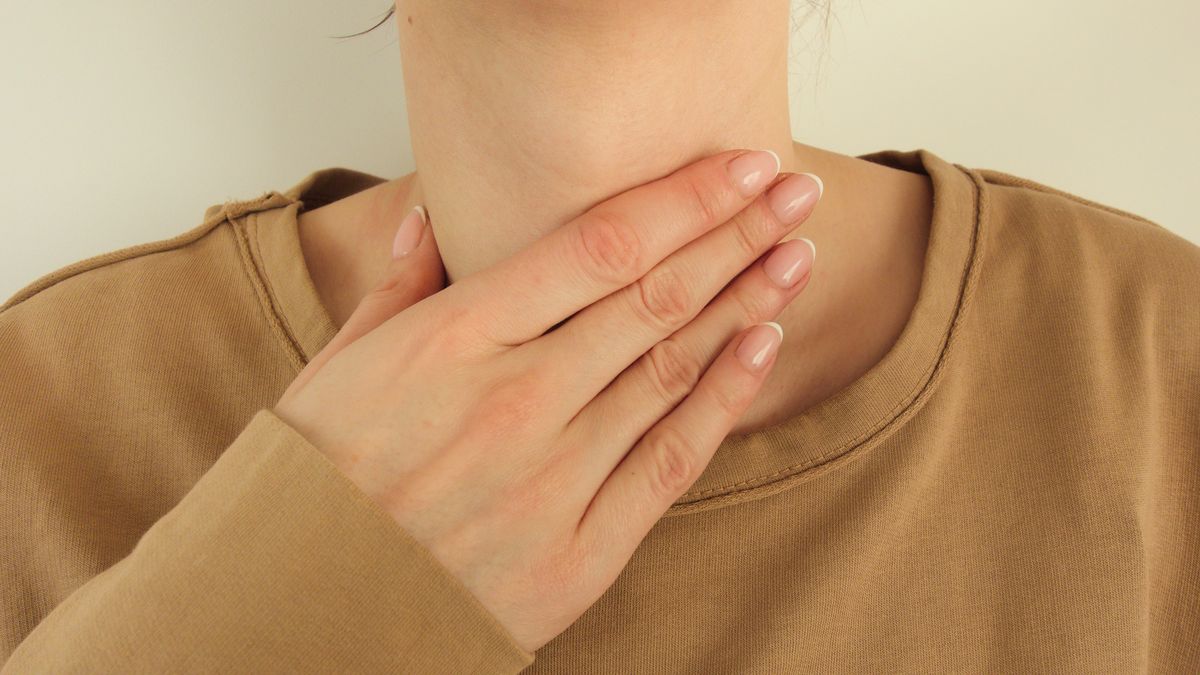 Young woman having sore throat is touching her ill neckYoung woman having sore throat is touching her ill neck. Healthcare and medical conceptPiotrekswat