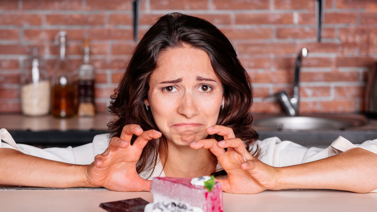 Kobieta na diecie odchudzającej ma przed sobą słodkości