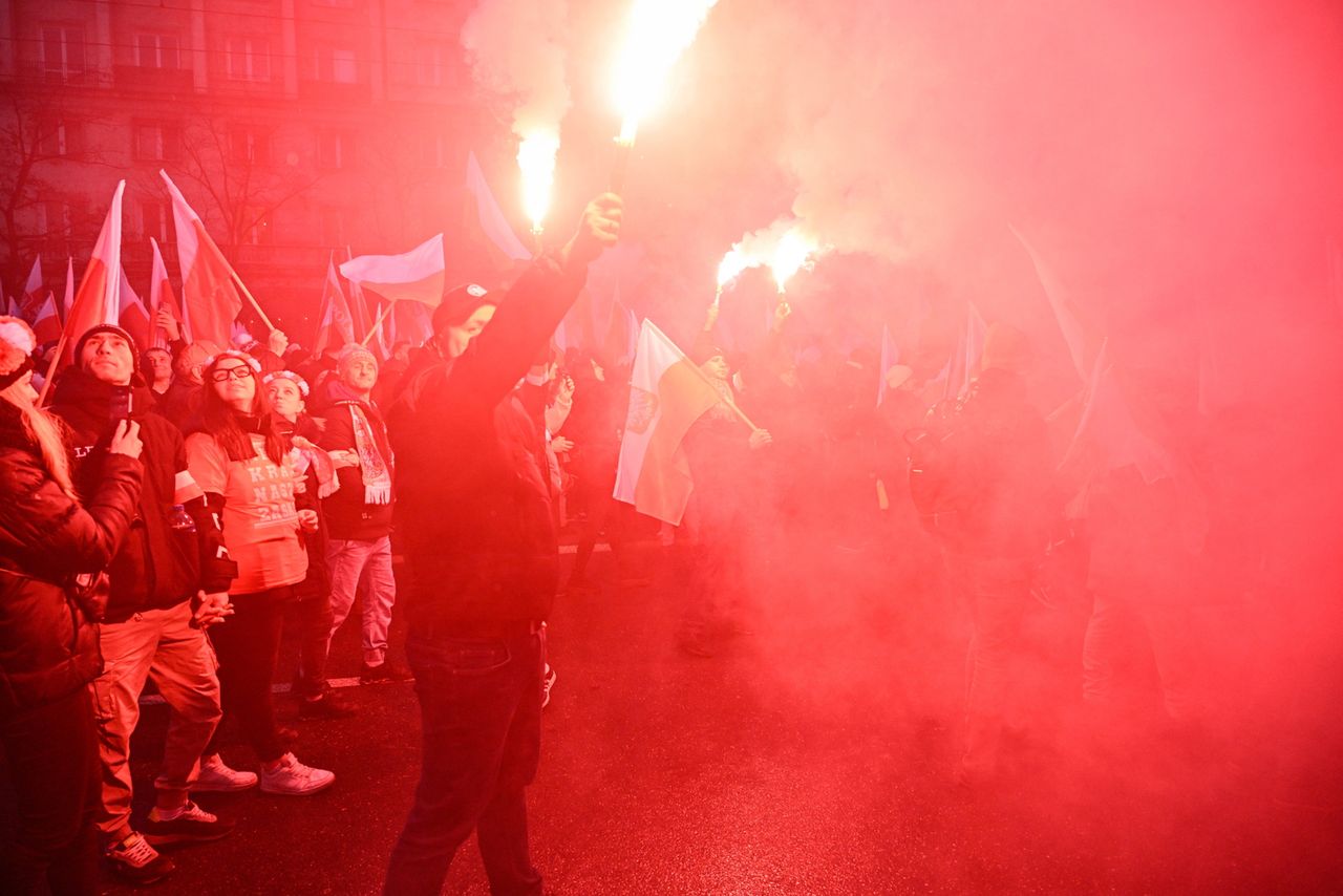 Zamaskowane osoby na Marszu Niepodległości. Słychać wybuchy, widać race