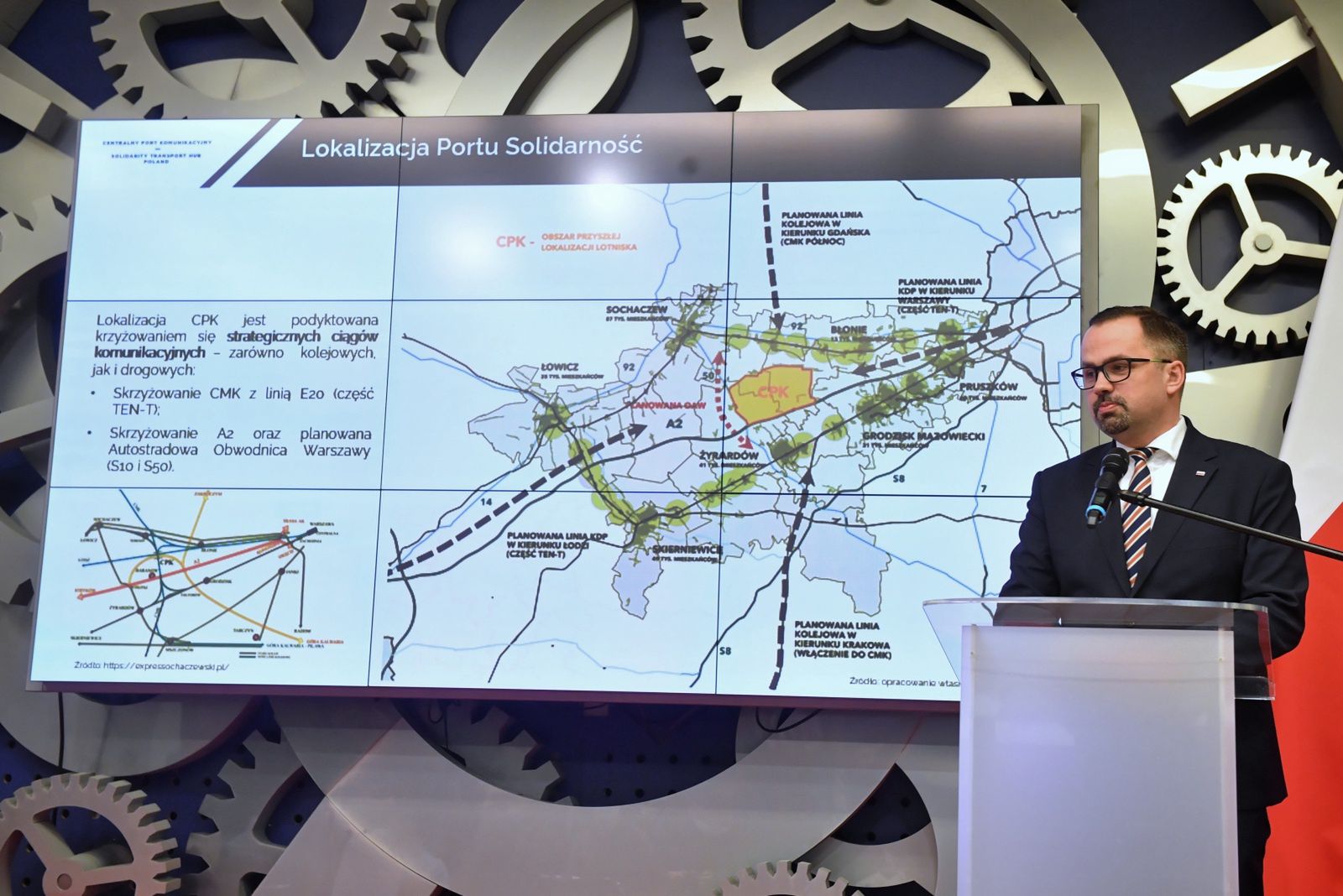 Marcin Horała, wiceminister infrastruktury i pełnomocnik rządu ds. CPK, na tle mapy pokazującej preferowaną lokalizację nowego lotniska. 
