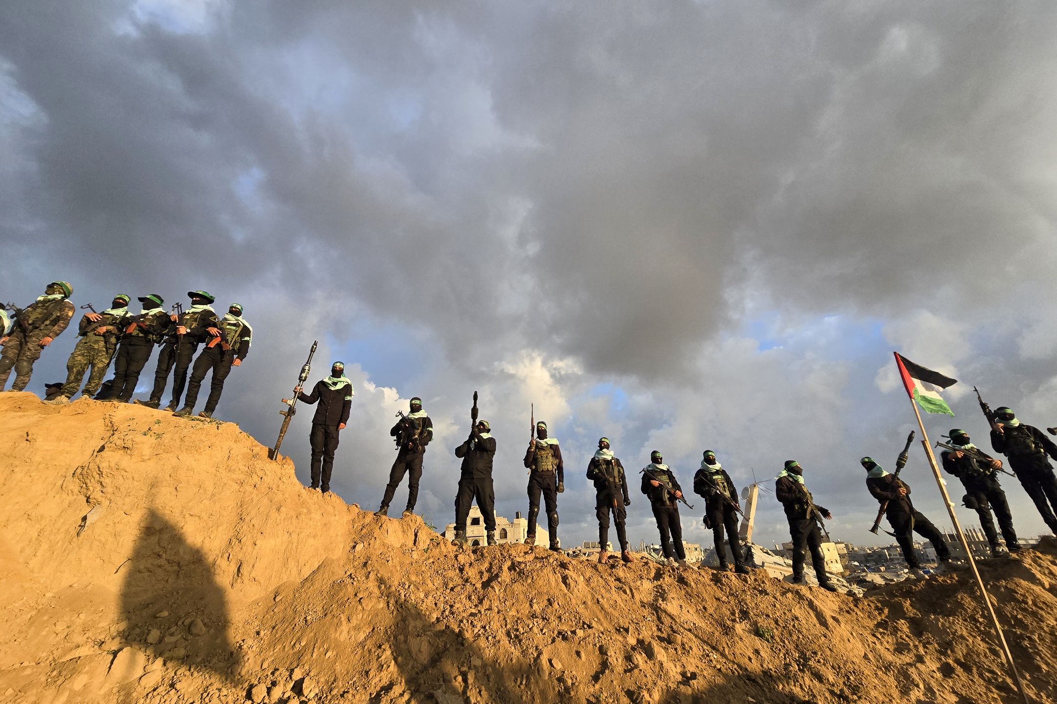 KHAN YUNIS, GAZA - FEBRUARY 20: Members of the Al-Qassam Brigades, the military wing of Hamas, take precautions around the cemetery in Bani Suheila municipality before the bodies of the Bibas family (three members) and Oded Lifshitz are handed over to the Red Cross teams as part of the Hamas-Israel prisoner-hostage swap agreement in Khan Yunis Governorate, Gaza on February 20, 2025. Al-Qassam Brigades announced that the four Israeli hostages were alive when captured, but the Israeli army killed them by deliberately bombing detention sites during the attacks in the Gaza Strip. (Photo by Ashraf Amra/Anadolu via Getty Images)