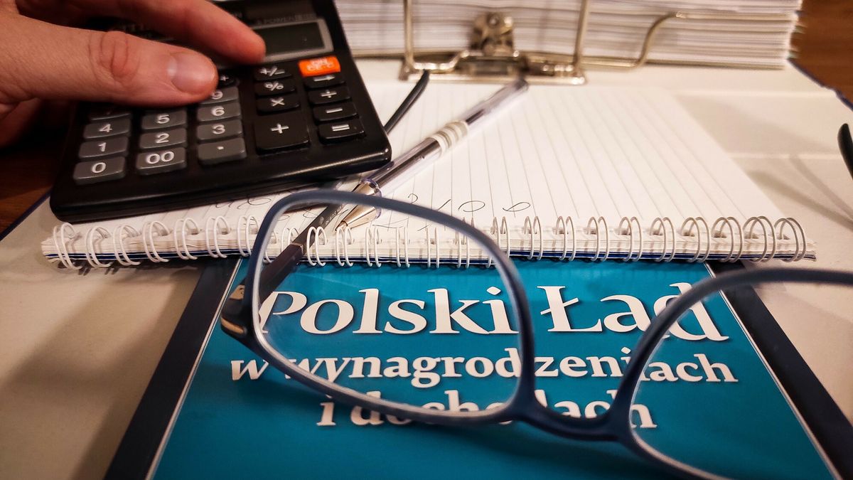 Na zdjęciu poradnik dotyczący Polskiego Ładu. Z tyłu zeszyt, długopis, segregator z dokumentami i kalkulator