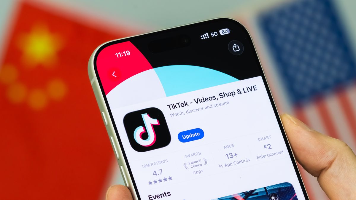 CHONGQING, CHINA - JANUARY 23: In this photo illustration, a person holds a smartphone displaying the TikTok application page on the Apple App Store, with the Chinese and U.S. flags visible in the background, on January 23, 2026, in Chongqing, China. In a post shared earlier in the day on Truth Social, U.S. President Donald Trump said he helped keep TikTok operating in the United States, citing efforts involving American investors and discussions with Chinese counterparts, and expressed appreciation for Chinese President Xi Jinping's approach toward allowing the deal to proceed amid ongoing U.S. national security scrutiny. (Photo illustration by Cheng Xin/Getty Images)