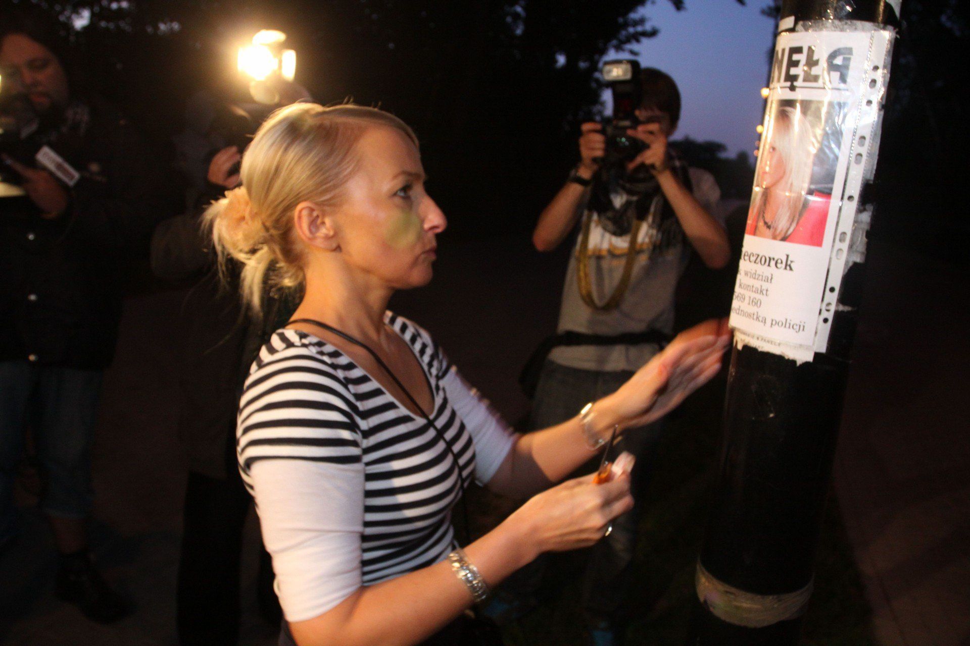 Iwona Kinda, podczas rozwieszania plakatu w pierwszą rocznicę zaginięcia córki.