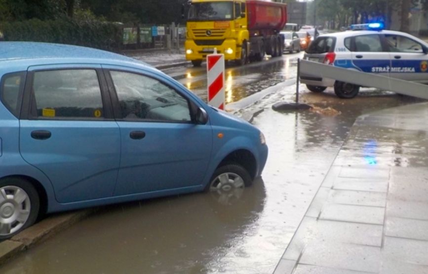 Warszawa. Chevrolet w wielkiej kałuży. Kierująca wykonała niefortunny manewr. Wydostać się z tej opresji pomogli jej strażnicy miejscy (Stołeczna Straż Miejska)