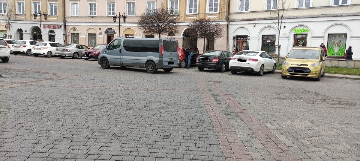 Policyjni wywiadowcy przeszukują samochód na Placu Zamkowym