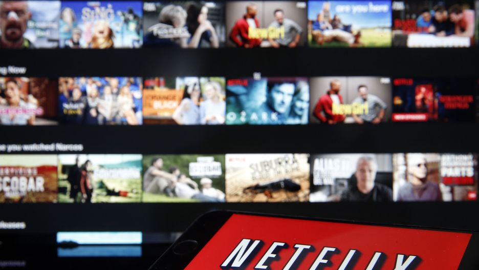 PARIS, FRANCE - MARCH 28: In this photo illustration, the Netflix media service provider's logo is displayed on the screen of an iPhone in front of a television screen on March 28, 2020 in Paris, France. Faced with the coronavirus crisis, Netflix will reduce visual quality for the next 30 days, in order to limit its use of bandwidth. (Photo by Chesnot/Getty Images)