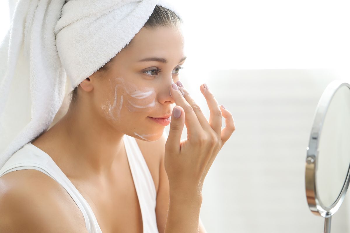 The woman applies sunscreen to her face.