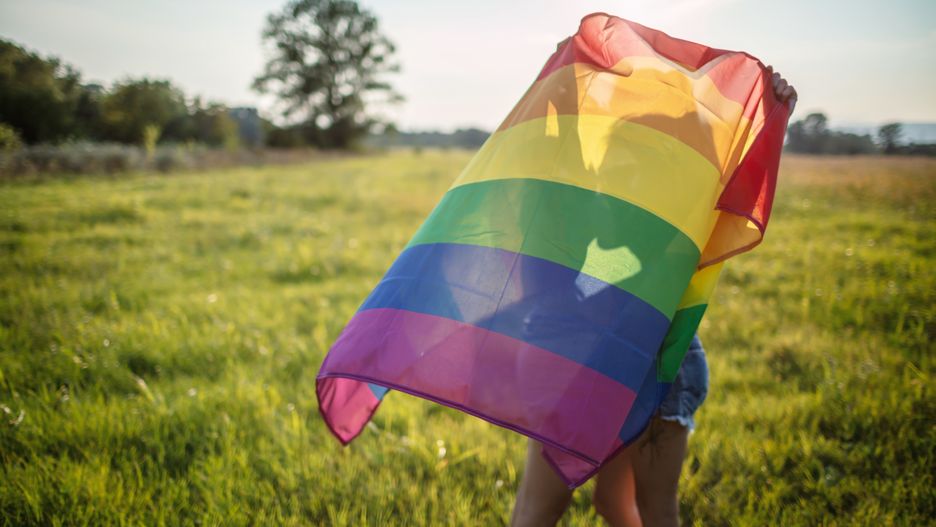 Lesbian women kissing behind the rainbow flag