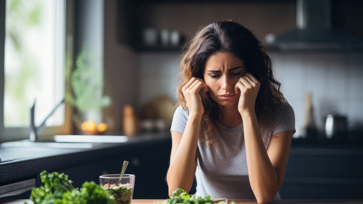 Smutna kobieta nad talerzem z sałatką