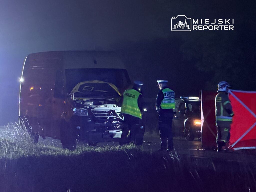 Policjanci i służby ratunkowe zabezpieczają miejsce wypadku drogowego przy uszkodzonym furgonie.