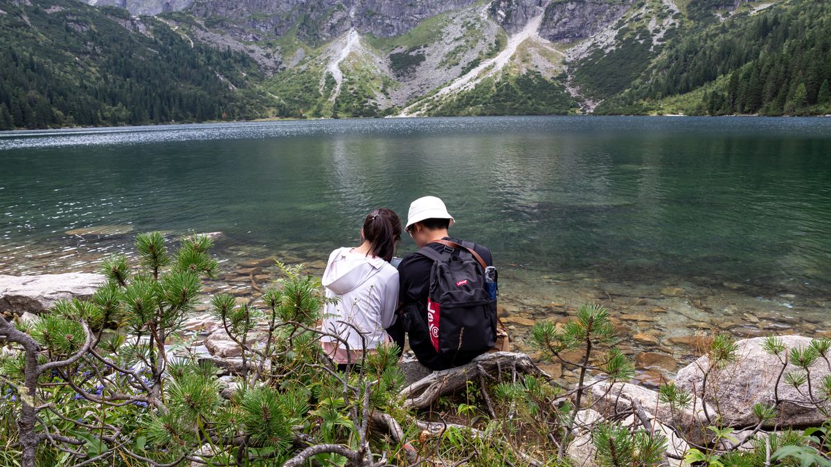 ZAKOPANE, MALOPOLSKIE, POLAND - 2025/08/29: A couple rests by Morskie Oko (The Sea Eye Lake) in Tatra National Park on the last weekend of school summer holidays. The Polish part of Tatra National Park welcomed 5.1 million visitors in 2024, with tourists coming mainly from Poland, the Czech Republic, Arab countries, and Ukraine. From January to June 2025, the park already recorded nearly 3 million visitors, over a million more than the same period in 2024. This sharp increase suggests the park is likely to surpass its 2024 record of 5.1 million visitors by the end of 2025. (Photo by Dominika Zarzycka/SOPA Images/LightRocket via Getty Images)
