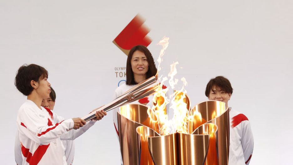 Azusa Iwashimizu, członkini reprezentacji Japonii w piłce nożnej kobiet, zapala pochodnię z uroczystego kotła z ogniem olimpijskim